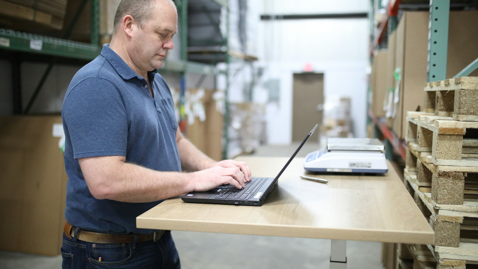 Man werkt op een laptop in een magazijn