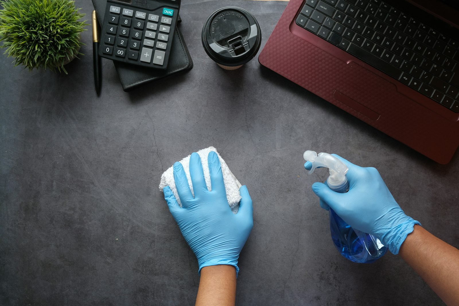 Handen met handschoenen maken een bureau schoon