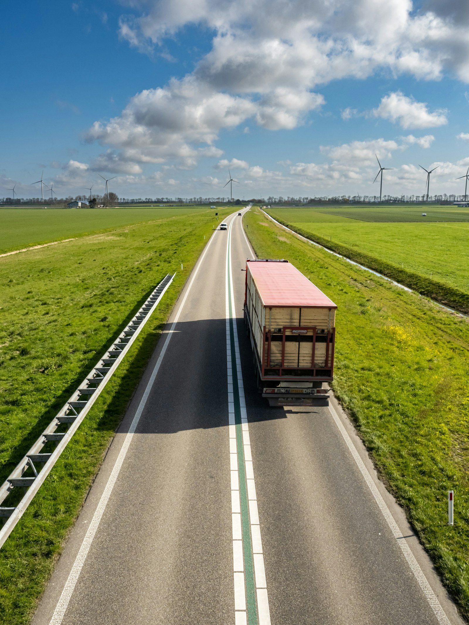Vrachtwagen op een polderweg met windmolens